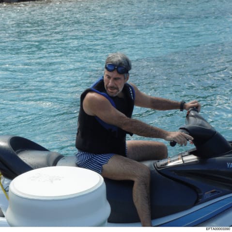 Jeffrey Epstein sitting on a jet ski by a dock.
