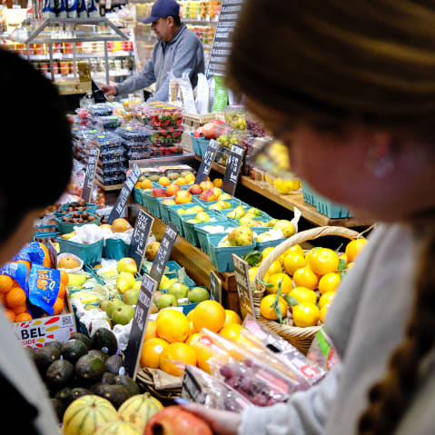 People shop for fruit in a grocery store ion NYC.