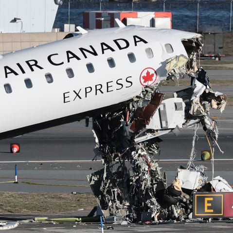 An Air Canada Express CRJ-900 sits on the runway after colliding with a Port Authority fire truck.