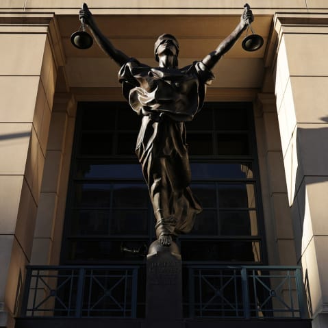 Light casts shadows over a statue of justice.