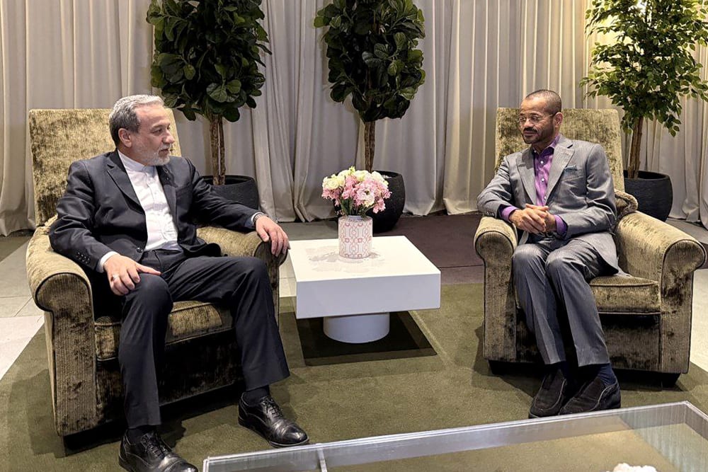 Abbas Araghchi, left, speaks to Badr Albusaidi as they sit side by side at arm chairs.