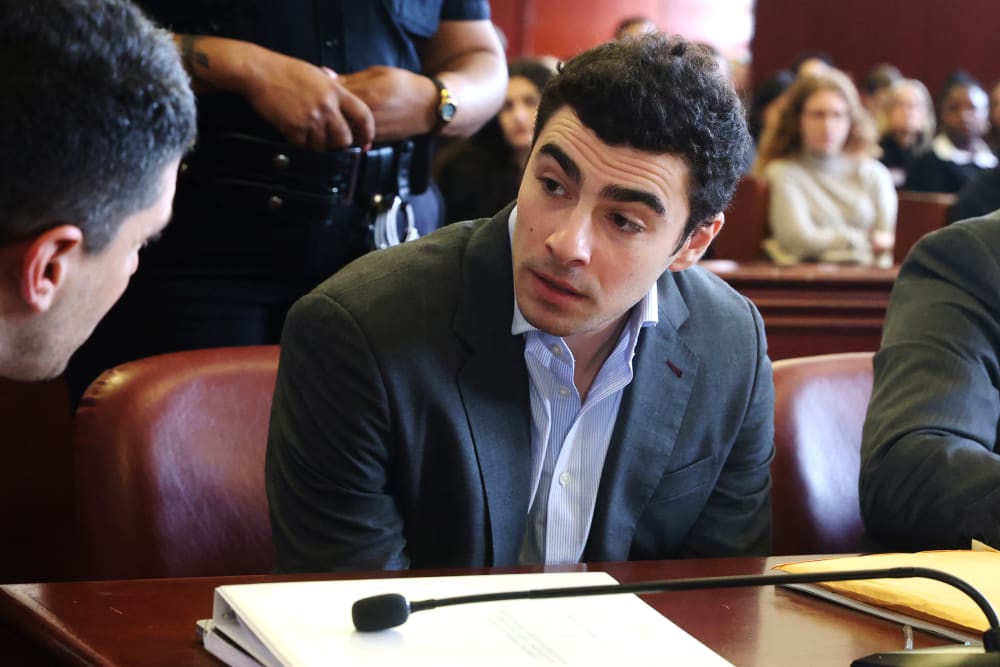 Luigi Mangione talks to a man as he sits in the court room.