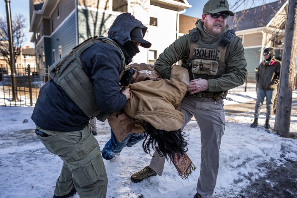 Two agents are carrying a person as they arrest them.