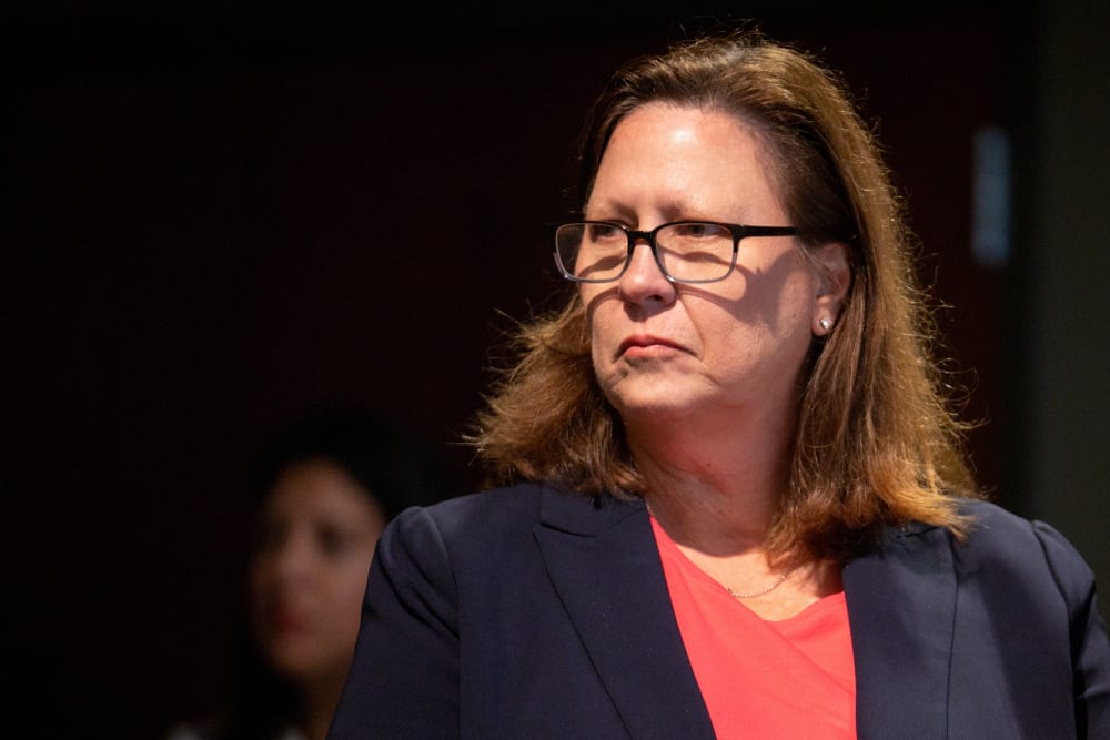 Julie Johnson looks on from the right side of the frame.