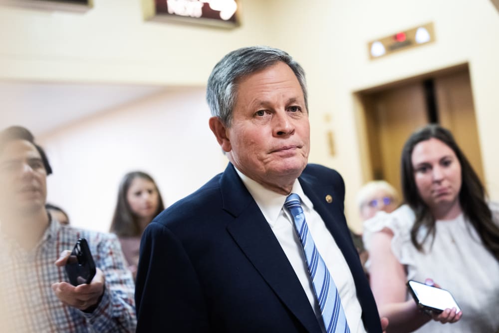 Steve Daniels walks in the direction of the camera as journalists follow him asking questions.