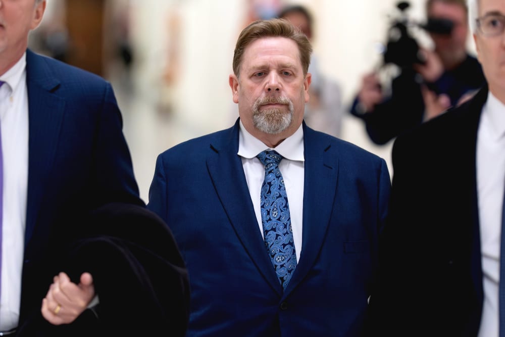 Darren Indyke walks behind two other men.