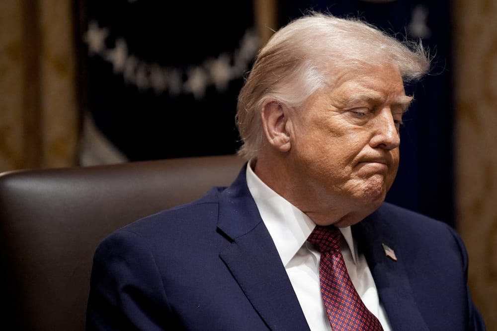 Donald Trump looks down looking upset as he sits in a meeting.