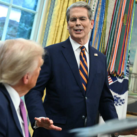 President trump, sitting-left, listens to Scott Bessent, standing-right, at the Oval Office.