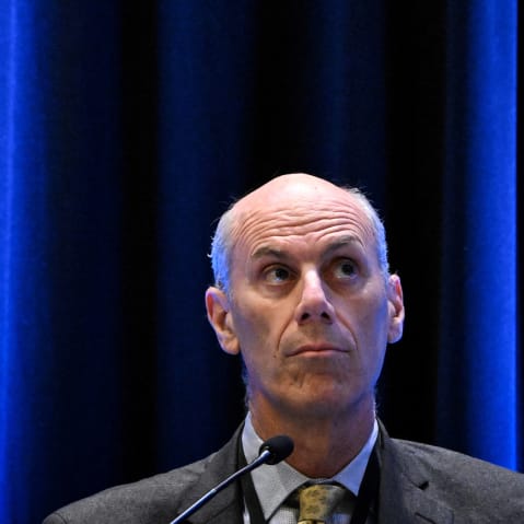 James Boasberg looks up in front of a plain blue background.