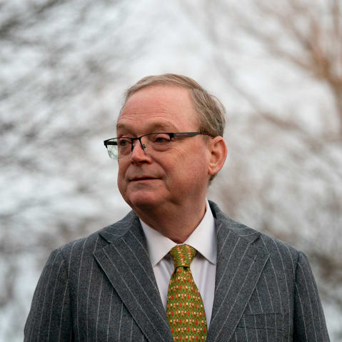 Kevin Hassett in a gray suit jacket and brightly colored tie, with bare trees behind him.