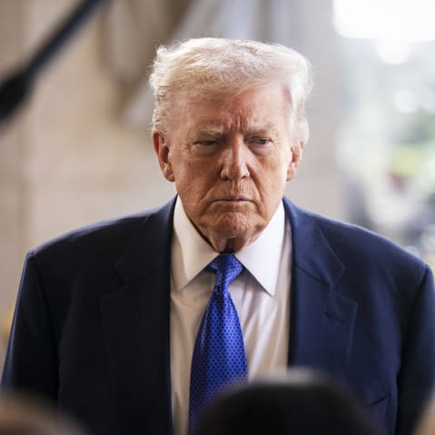 President Trump seen standing in front of reporters, looking displeased.