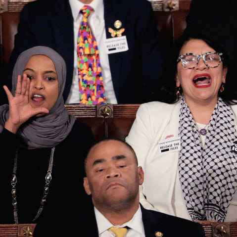 Ilhan Omar has her hand around his mouth as she and Tlaid yells.