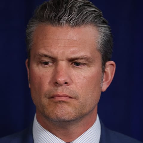 Mark Kelly smiling; Pete Hegseth looking down.