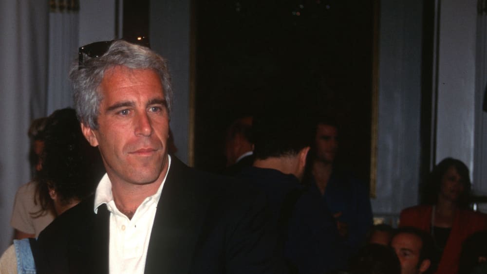 Jeffrey Epstein talks to another guest.