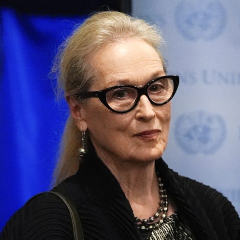 Merly Streep looks on while wearing black framed glasses.