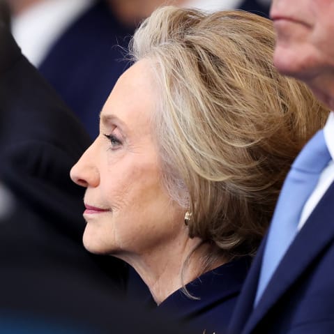 Hillary Clinton is seen from the side among a crowd of people.