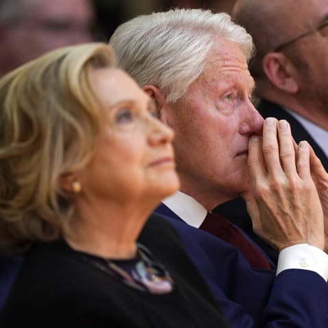 Hillary Clinton, left, looks up as she sits next to her husband Bill Clinton.