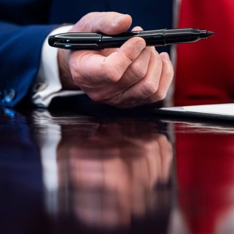 A close up of President Donald Trump's hand holding a pen.
