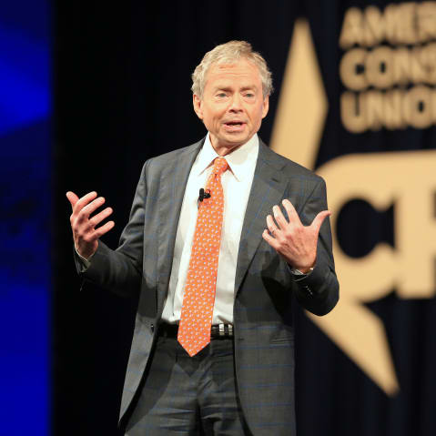 Don Huffines stands on the stage, his hands are half way up as he speaks.