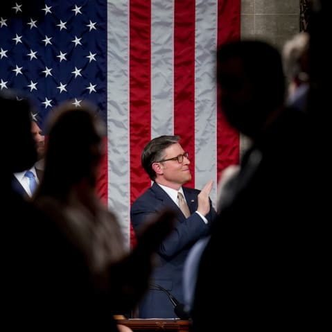 Mike Johnson is seen in the middle of the frame while he applauds.