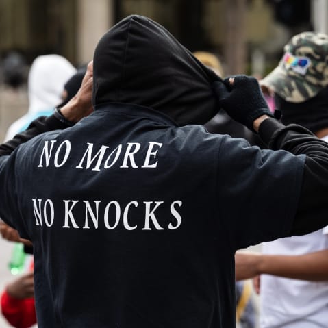 a person is seen from behind as he adjusts his black hoodie.