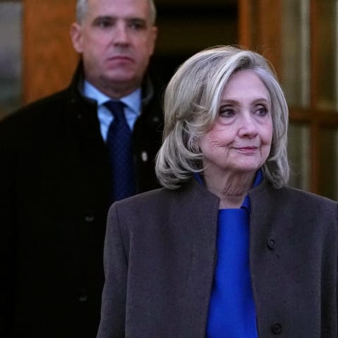 Hillary Clinton, right, looks off while walking out from a double set of doors.