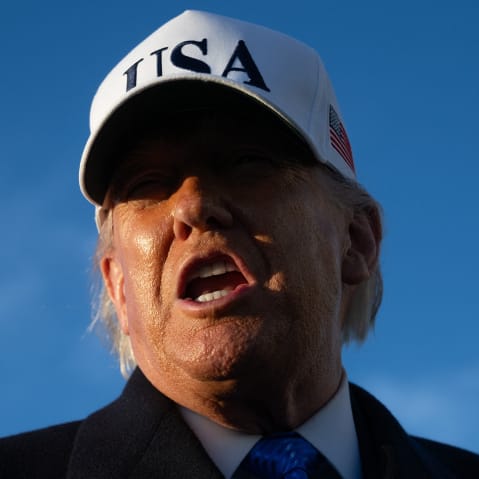 Donald Trump with his mouth open. A white baseball cap that "USA" casts a shadow on his face, obscuring his eyes.