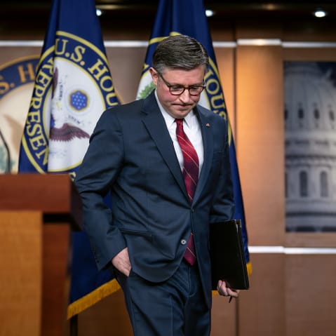 Mike Johnson walks up to a podium with his head down and hand in his pocket.