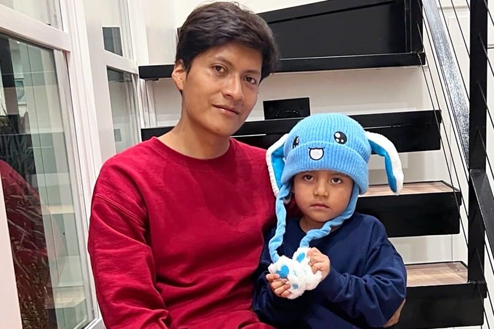 5 year old Liam Ramos, right, sits next to his dad on the steps of a staircase after being released from ICE detention.