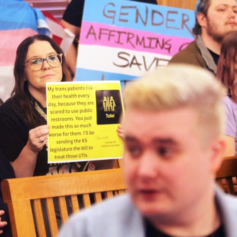 Several people hold up pro-transgender rights signs.