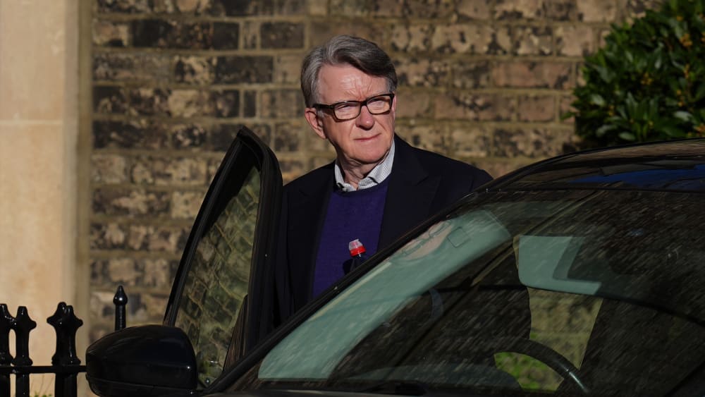 Peter Mandelson enters the driver's side of a car.
