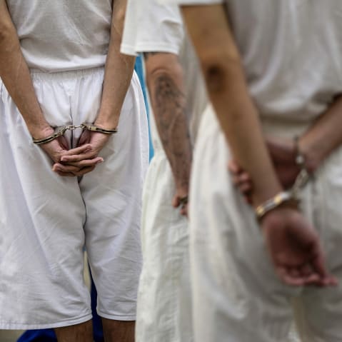 Accused gang members in handcuffs wait for a medical exam at the Counter Terrorism Confinement Center in Tecoluca, El Salvador.