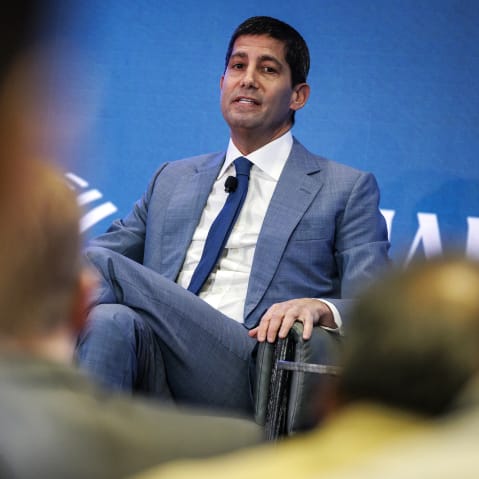 Kevin Warsh sitting on stage seen through heads of the audience.