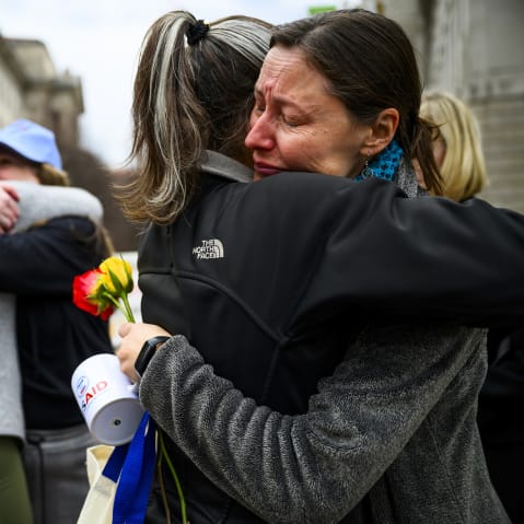 Prarie Summer, a USAID contractor for almost 10 years, right, cries as she embraces a Alexandra Jung after leaving the agency's former offices at the Ronald Reagan Building and International Trade Center.