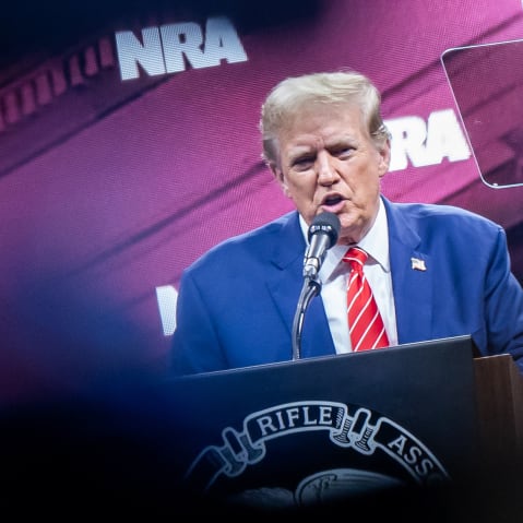 President Trump speaks at an NRA convention on stage.