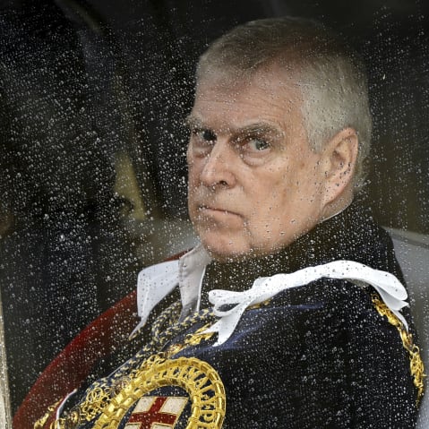 Former Prince Andrew is seen through a car window on a rainy day.