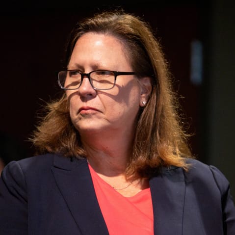 Julie Johnson looks on from the right side of the frame.