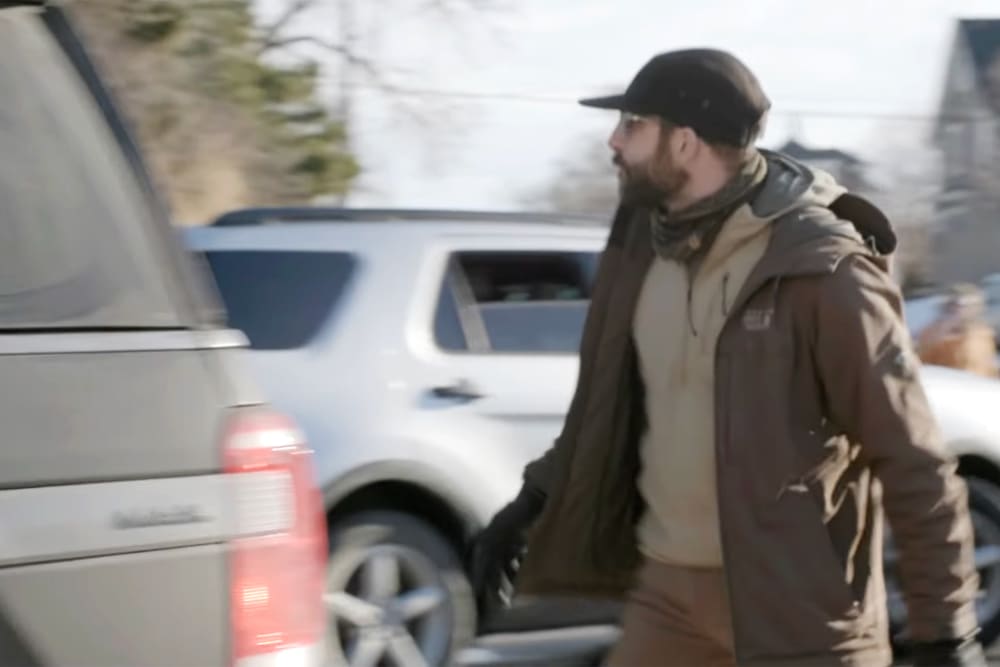 Alex Pretti is yelling at ICE agents as they drive away in their SUV. Pretti is on the right of the frame.