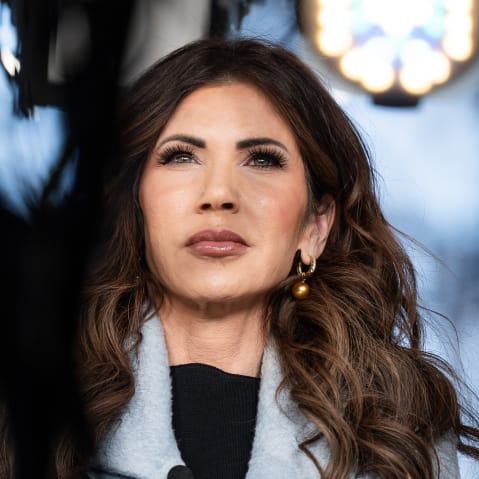 Kristi Noem can be seen through the TV cameras and lights during an interview.