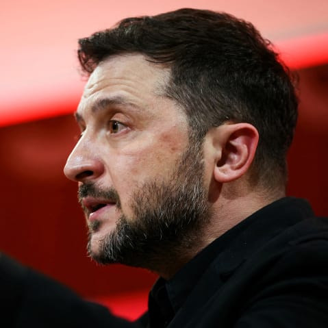 In this closeup photo, Zelenskyy can be seen from his left side with his left hand up making a gesture as he speaks.
