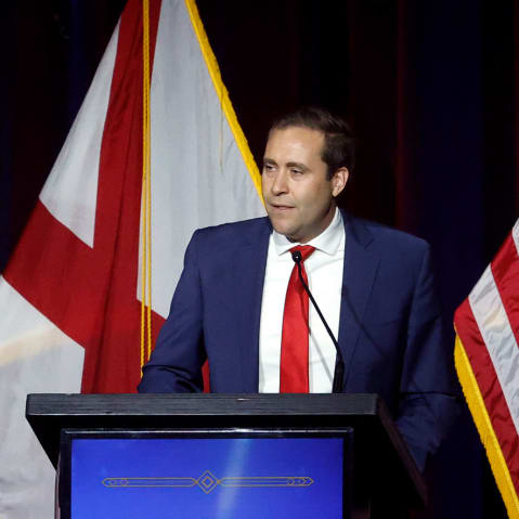 John Wahl stands behind a podium that says "Trump Victory Dinner & Reception with Donald Trump, Jr."