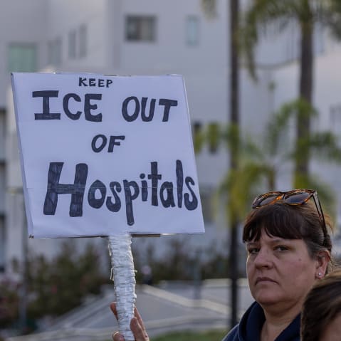 A person holds a sign that reads "Keep ICE out of hospitals."