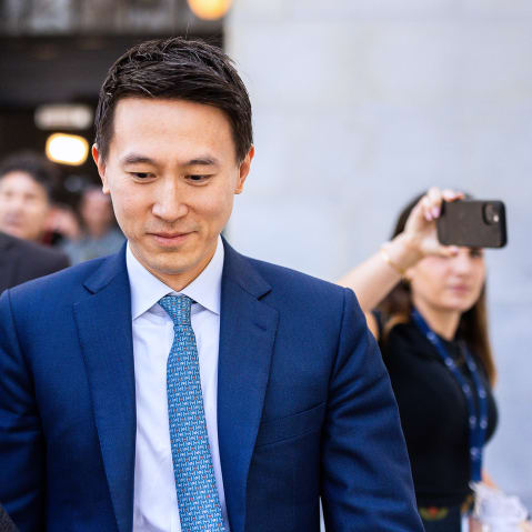 Shou Zi Chew smiling and looking down, surrounded by people.