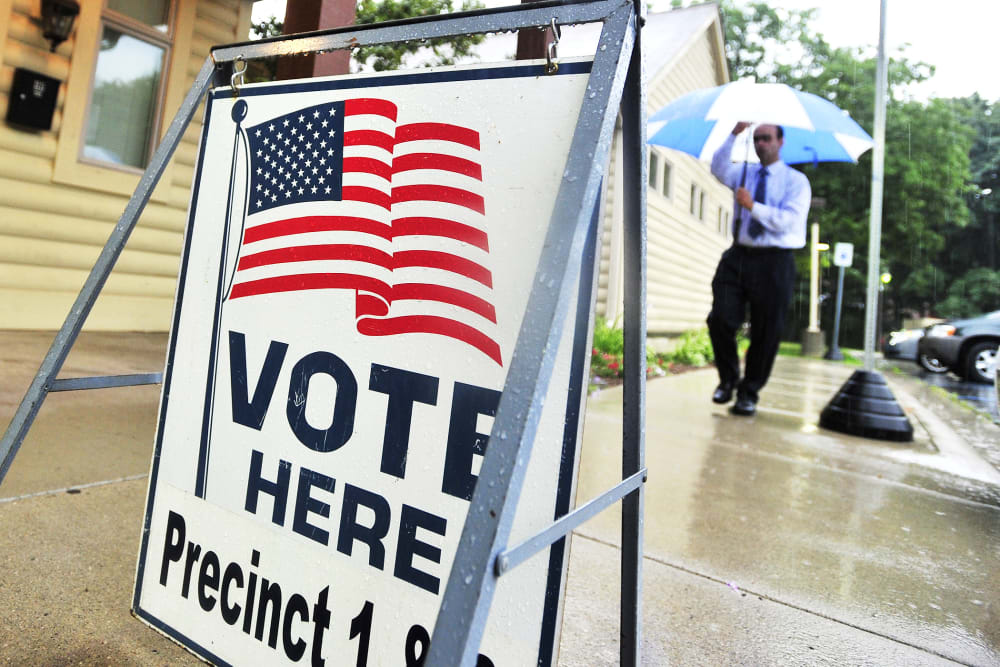 A man walks in the rain to vote at the Rochester Community House in Rochester, Mich. on Tuesday, Aug. 5, 2014.