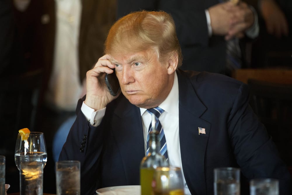 Republican presidential candidate Donald Trump listens to his mobile phone during a lunch stop, Feb. 18, 2016, in North Charleston, S.C. (Photo by Matt Rourke/AP)
