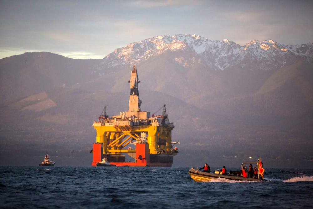 A small boat crosses in front of an oil drilling rig as it arrives in Port Angeles, Wash. on April 17, 2015. (Photo by Daniella Beccaria/seattlepi.com/File/AP)