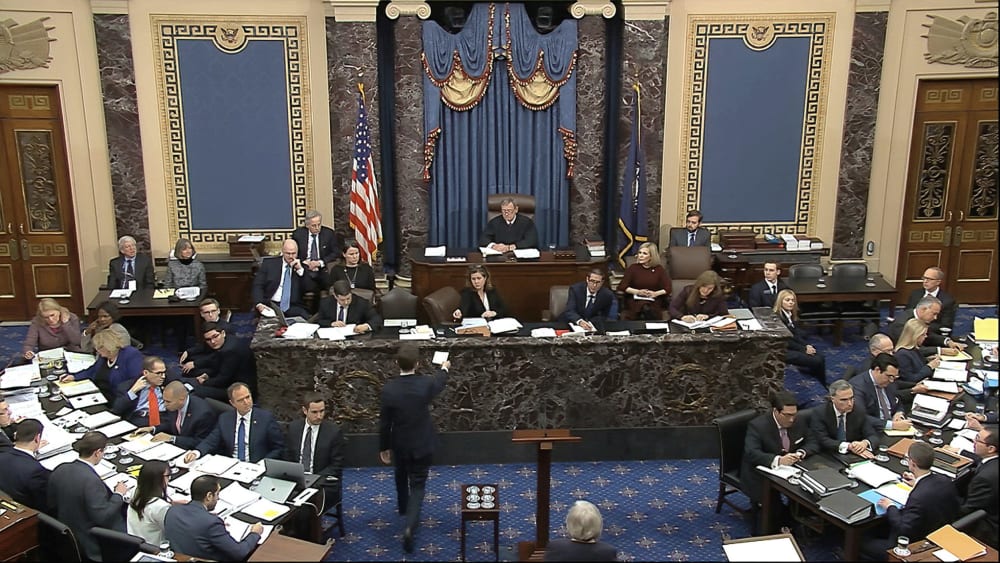 Image: A Senate page brings the first question to presiding officer Chief Justice of the United States John Roberts from the majority to read during the impeachment trial against President Donald Trump in the Senate at the U.S. Capitol