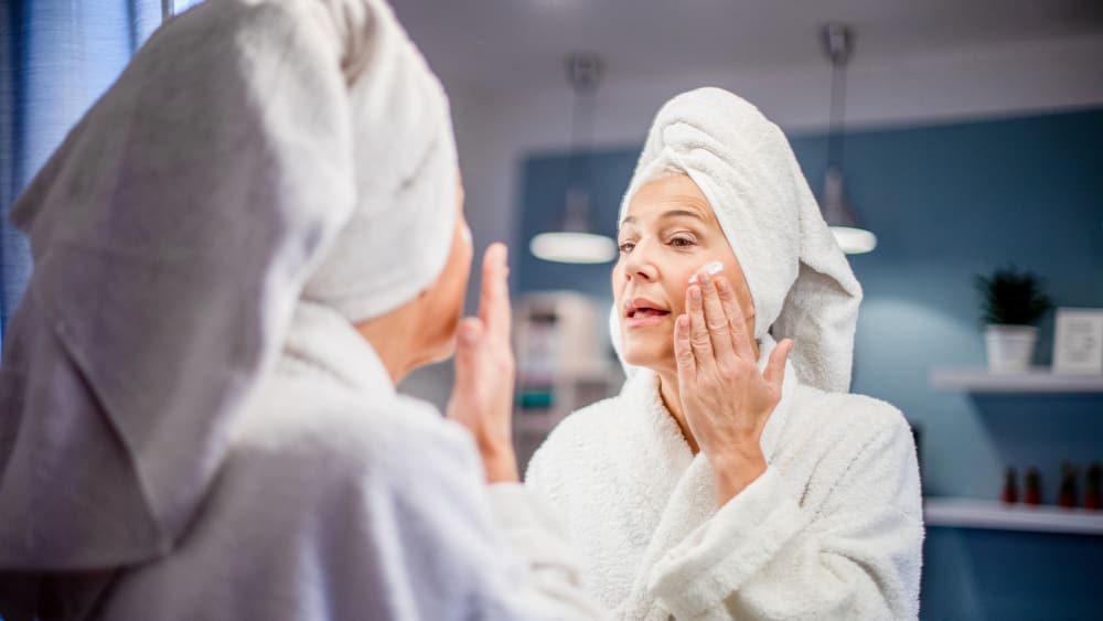 Mature woman applying face cream.