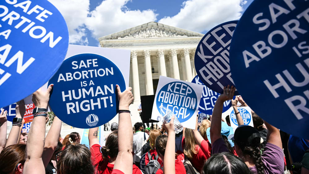 People hold signs saying "Safe Abortion is a Human Right" and "Keep abortion legal"