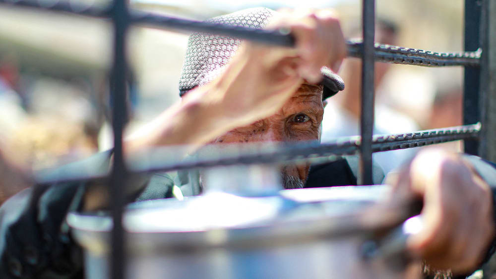 An elderly Palestinian man waits to get rice from a charity kitchen providing food in the west of Gaza City.